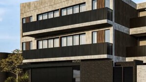 Um edifício moderno de vários andares com telhado plano, janelas grandes e garagem.
