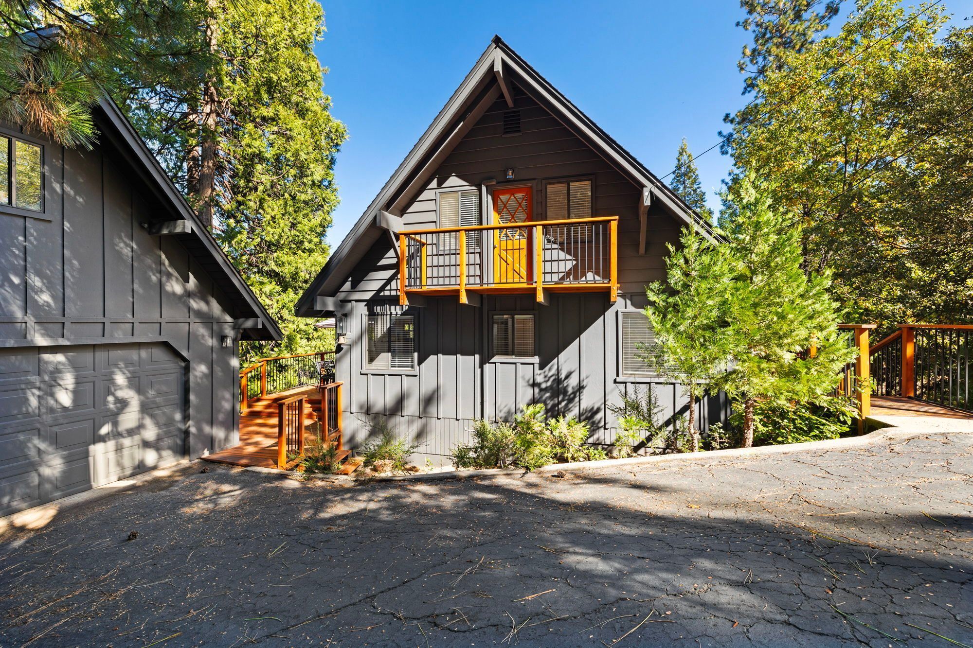 A two-story cabin with a balcony, surrounded by trees.