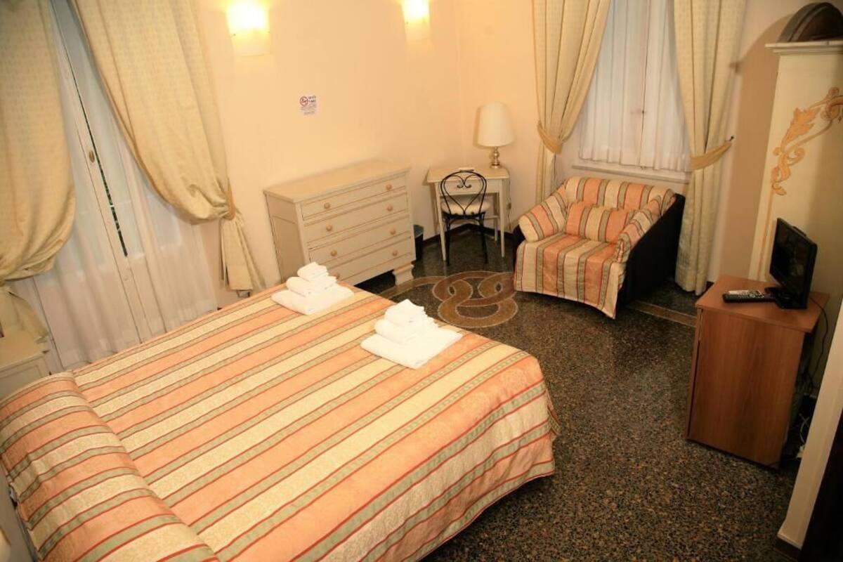 Une chambre d’hôtel avec un lit, une chaise, un bureau et un téléviseur.