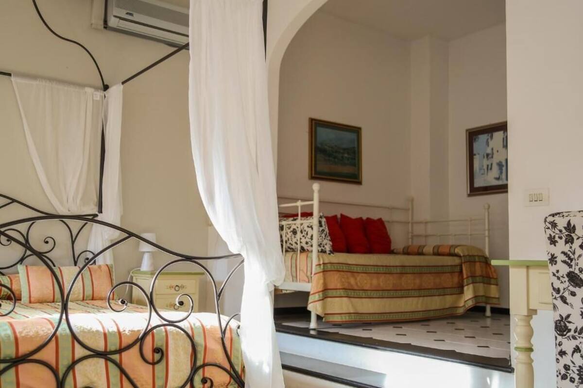 Une chambre à coucher avec un lit en métal, une table de chevet, une chaise et un lit recouvert d’une couverture à rayures.