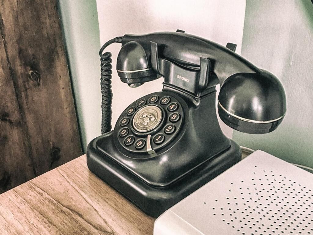 Un teléfono antiguo negro sobre una mesa de madera.
