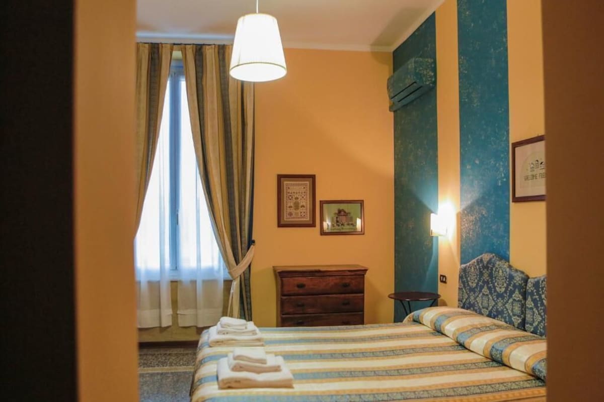Una habitación de hotel con una cama, un tocador, una mesita de noche y una ventana con cortinas.