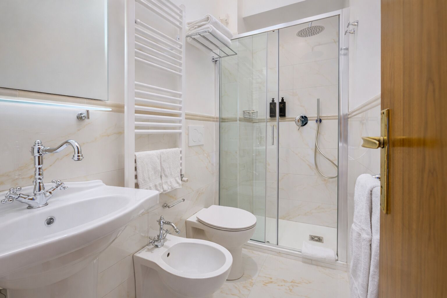 A modern bathroom with a glass-enclosed shower, a white sink, and a bidet.