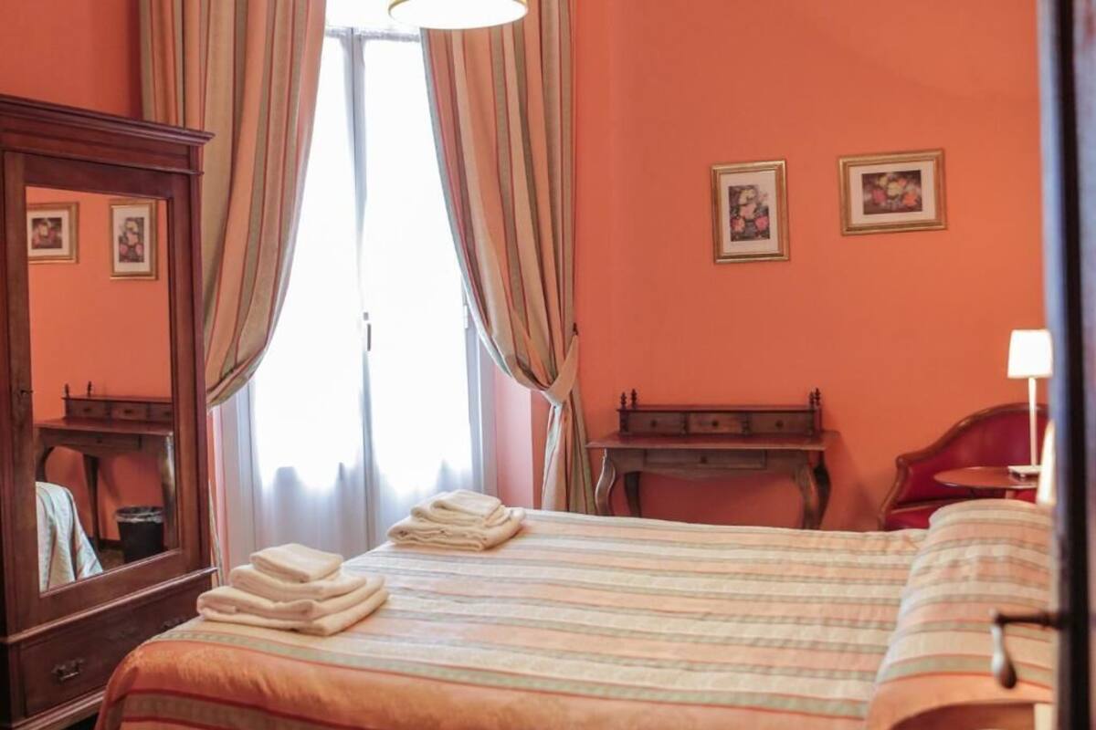 Une chambre d’hôtel avec un lit, une commode en bois, un bureau et une chaise.