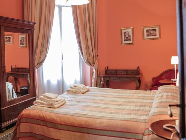 Una habitación de hotel con una cama, un aparador de madera, un escritorio y una silla.