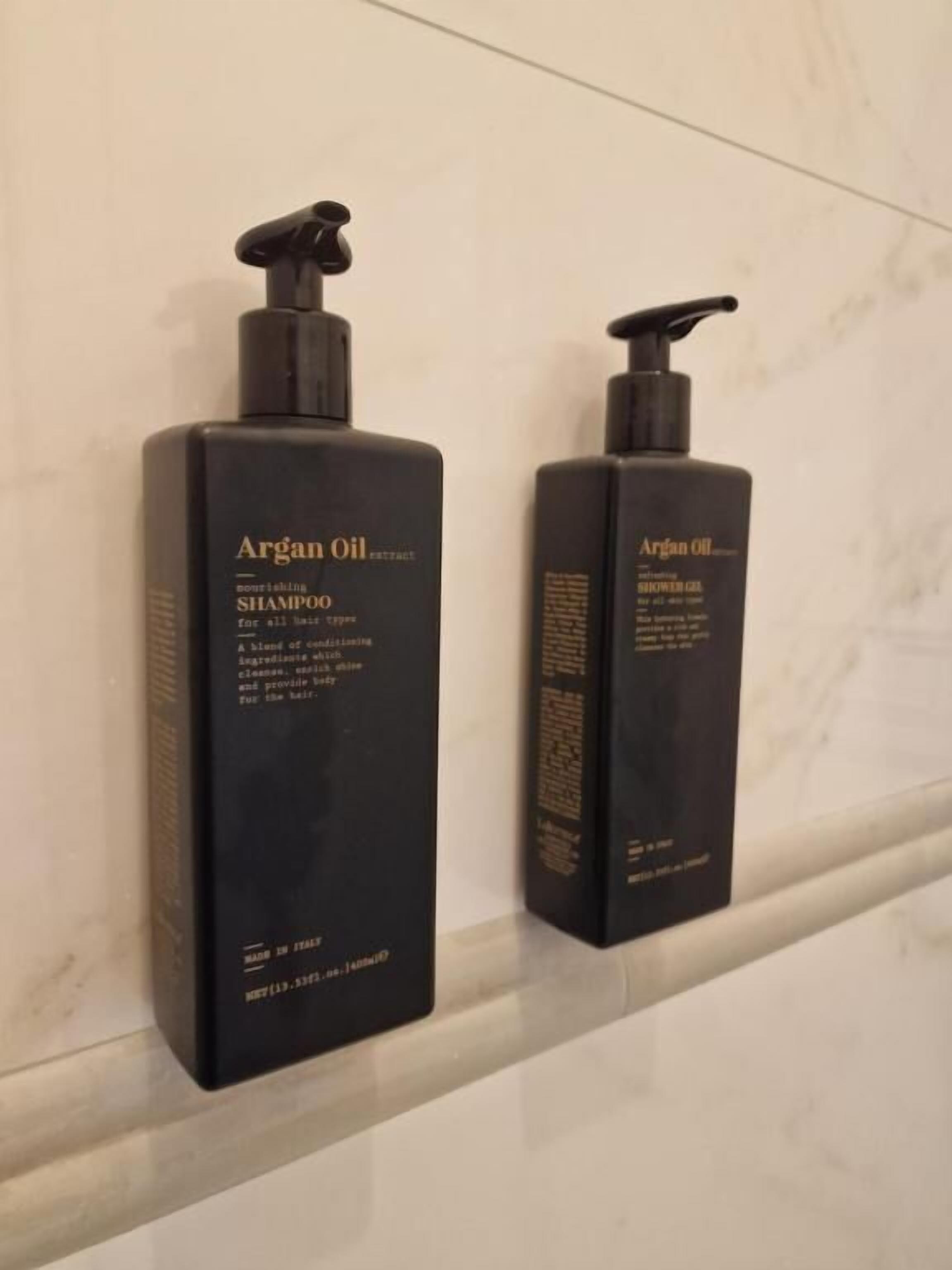 Duas embalagens de shampoo e gel de banho com óleo de argan sobre uma superfície de mármore.
