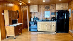 A kitchen with wooden cabinets, a refrigerator, and a stove. - Peace Cottage on the Water-Rustic Charm & Lakefront Living!! (Faribault)