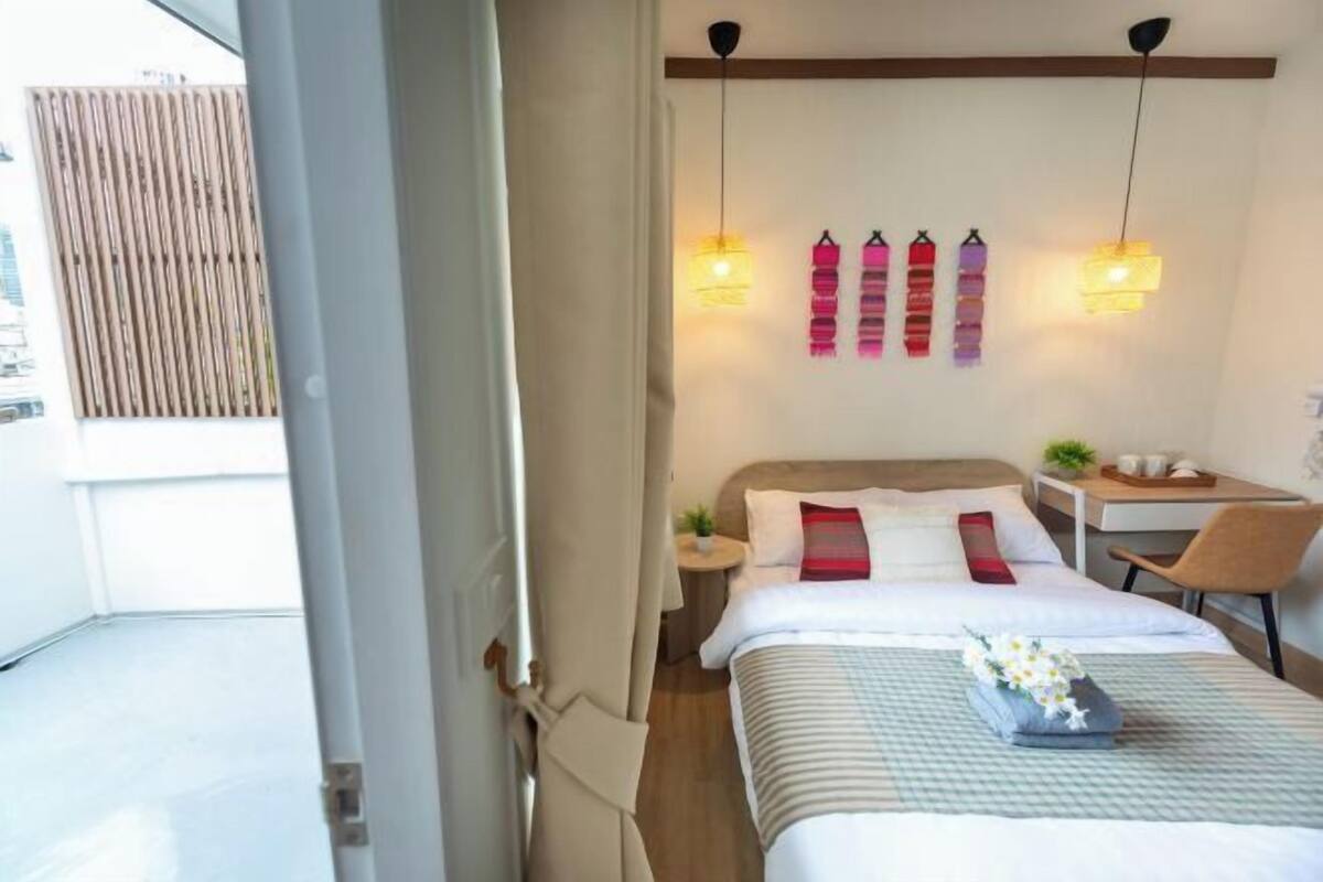 Ein Hotelzimmer mit Bett, Nachttisch, Sessel und Schreibtisch mit Stuhl.