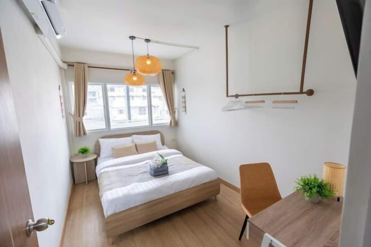 Ein modernes Hotelzimmer mit einem großen Bett, einem Schreibtisch und einem Fenster mit Vorhängen.
