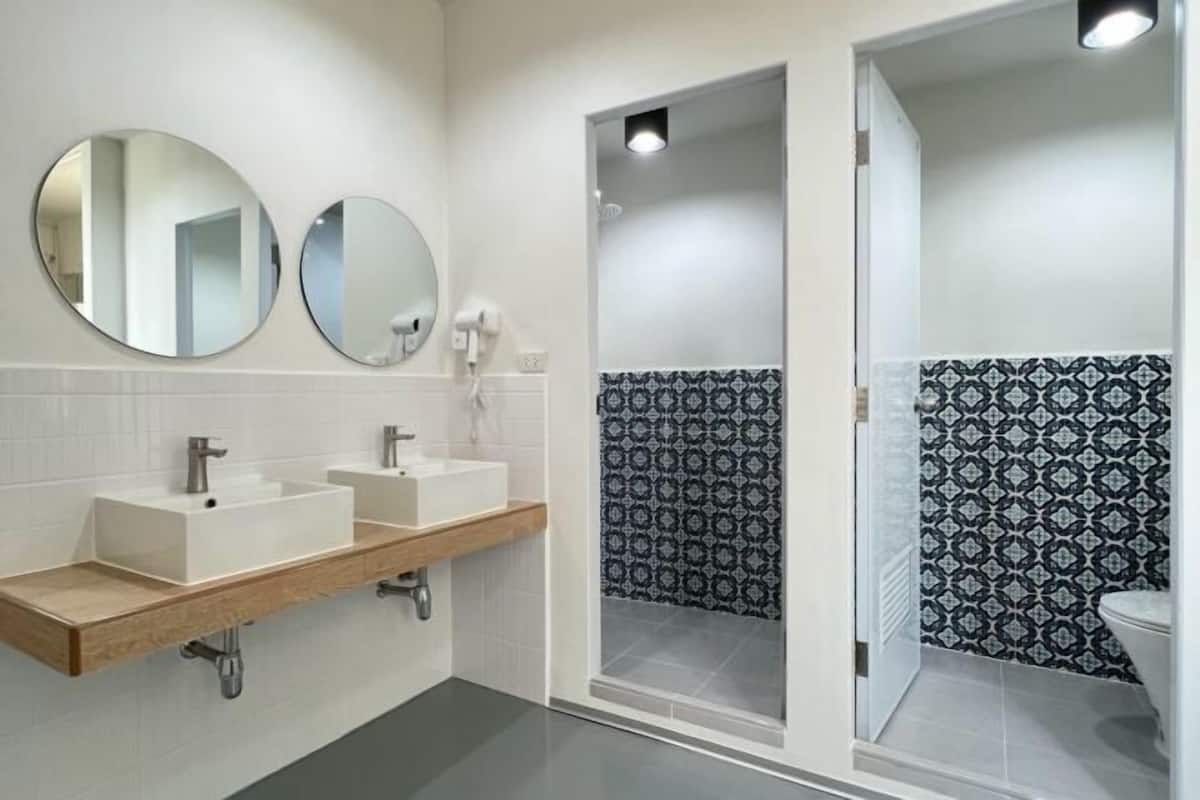 Ein modernes Badezimmer mit zwei Waschbecken, einer Dusche und gemusterten Fliesen.