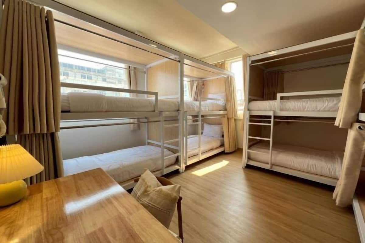 Ein Hotelzimmer mit Etagenbetten, einem Holztisch, einer Lampe und Vorhängen.