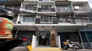 Un bâtiment dont la devanture porte l’inscription « EASE » et devant lequel est garée une moto.