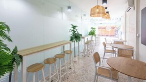 Un café moderne avec des tabourets de bar, des tables rondes et des lampes en osier suspendues au plafond.