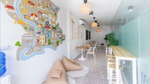 Un hall d’hôtel moderne avec une grande carte murale, des espaces de détente et une longue table.