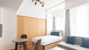 A hotel room with a bed, a sofa, a table, a chair, a TV, and a wardrobe. - Daffitto Tennozu (Tokyo)