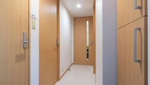 A narrow hallway with wooden doors and a light-colored floor. - Daffitto Tennozu (Tokyo)