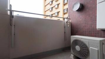 Quarto com porta deslizante fechada, ar condicionado fixado na parede e janela com vista para um edifício.