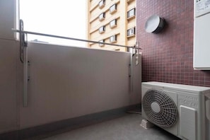 A room with a sliding door, a wall-mounted fan, and a view of a building with multiple windows. - Daffitto Tennozu (Tokyo)