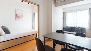 A room with a bed, a table, chairs, a sofa, and an air conditioning unit. - Daffitto Tennozu (Tokyo)