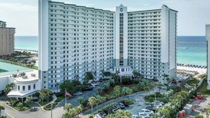A high-rise hotel with multiple floors, a central courtyard, and a view of the beach. - 🦩Book Me Baby! Beach Penthouse at Pelican Beach🦩 (Destin)
