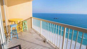 A balcony with a view of the ocean, a small table, two chairs, and a railing. - 🦩Book Me Baby! Beach Penthouse at Pelican Beach🦩 (Destin)