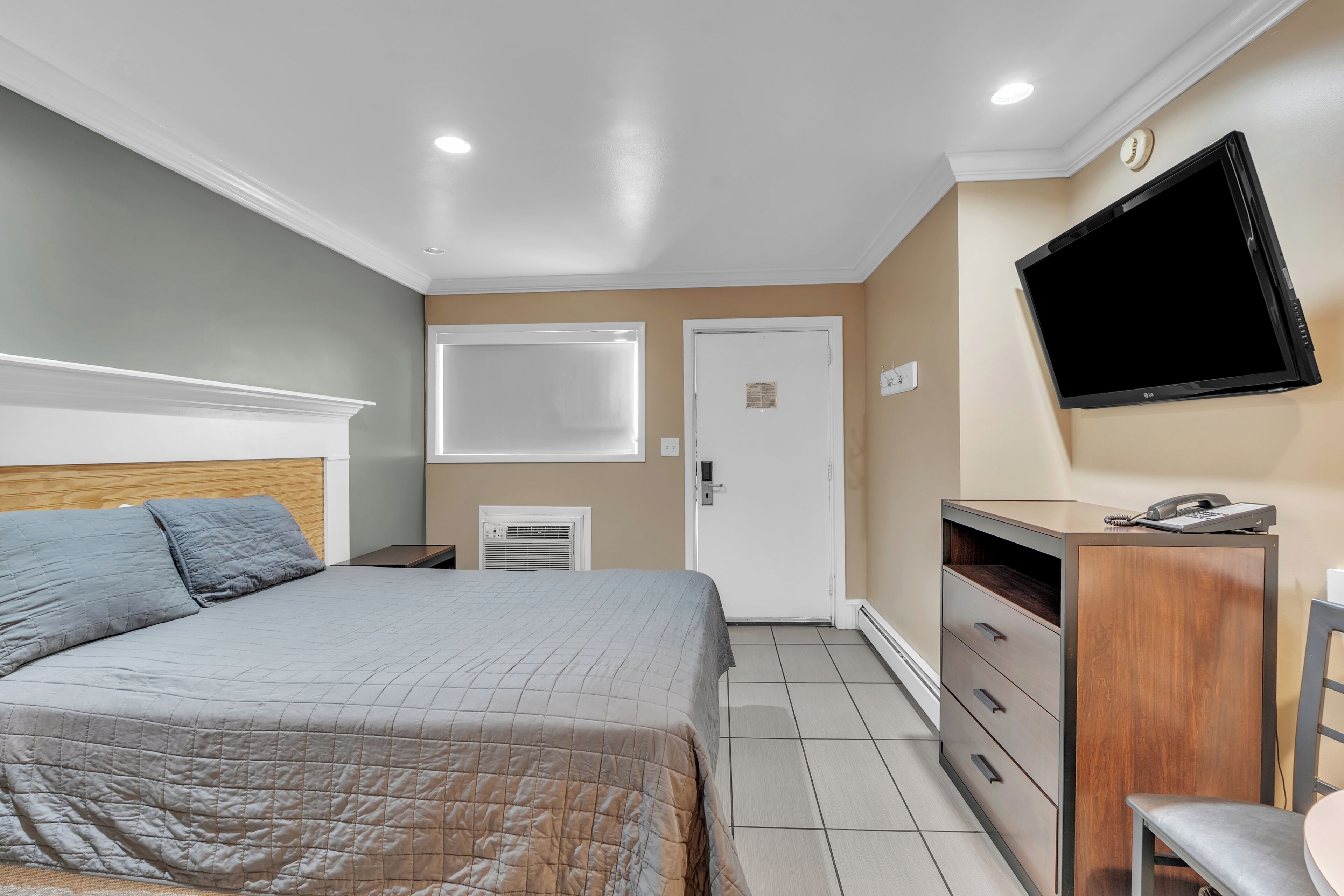 Une chambre à coucher avec un lit, un bureau, une chaise, une télévision et une porte.