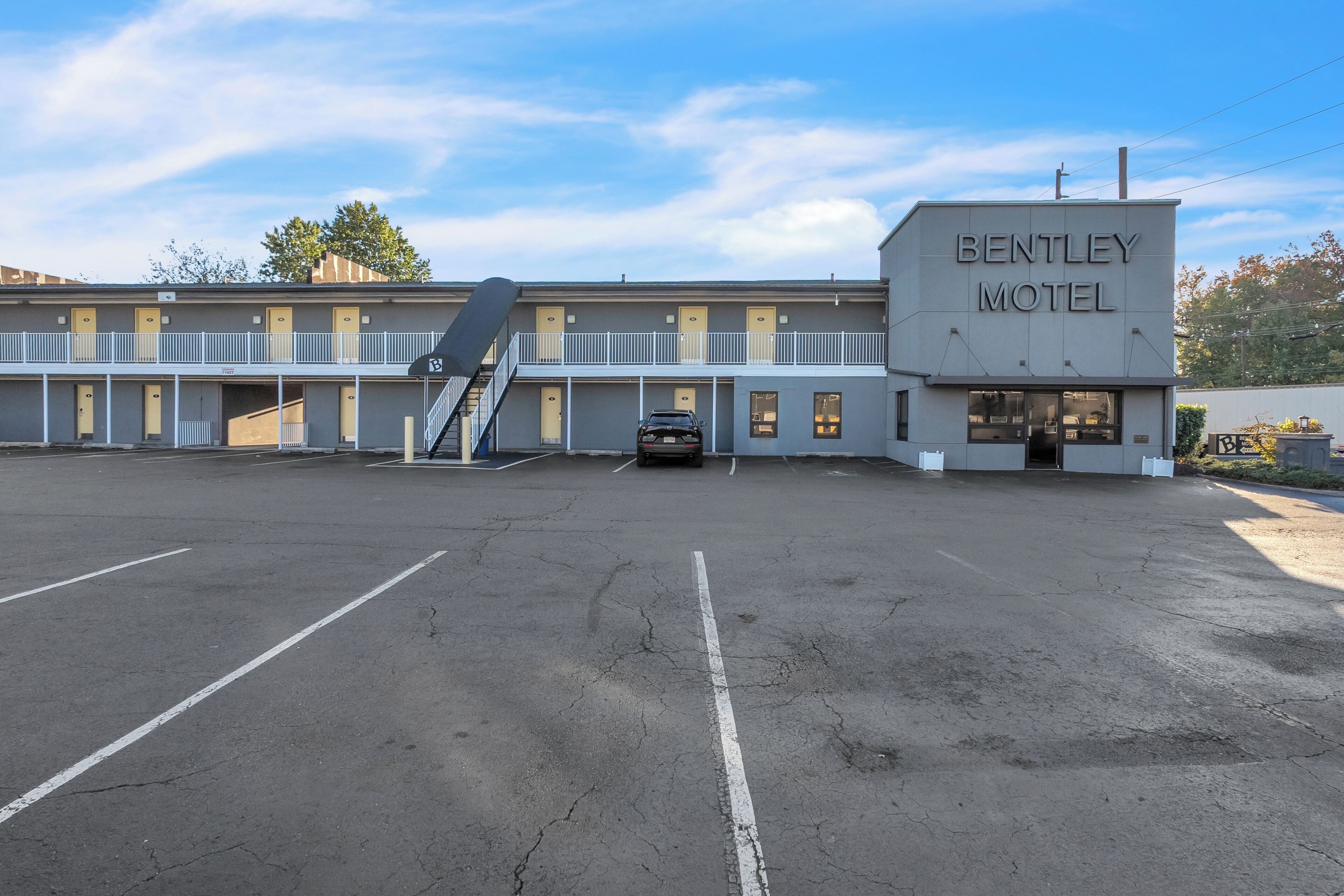 Een motel met een bord waarop 'BENTLEY MOTEL' staat, en een parkeerplaats ervoor.