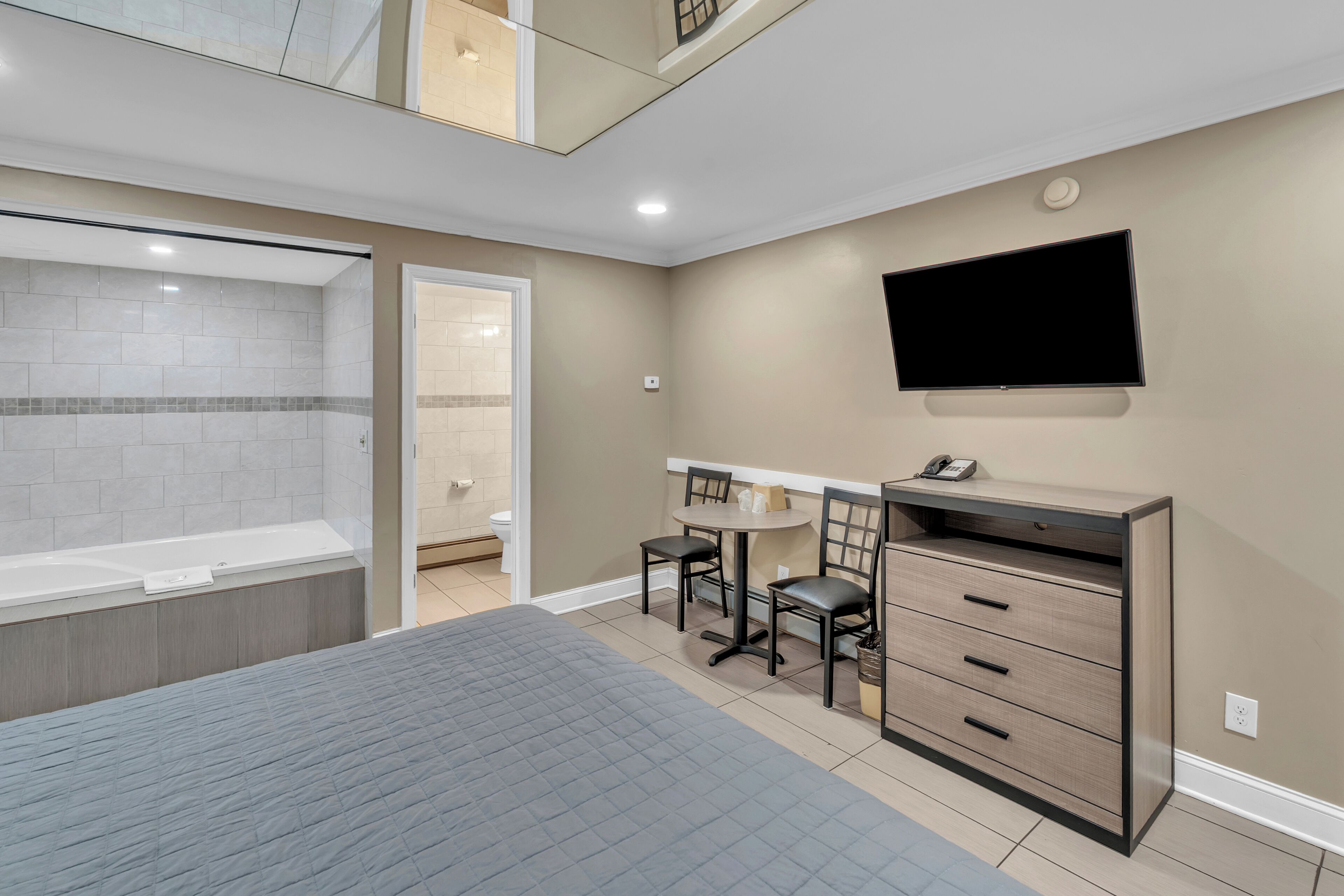Une chambre d’hôtel comprenant un lit, un bureau avec des chaises, une télévision et une salle de bain avec une baignoire et des toilettes.
