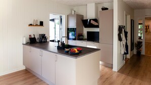Una cocina moderna con una isla central, armarios blancos y piso de madera.