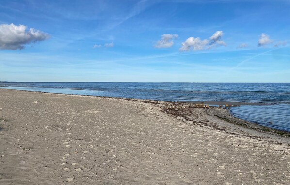 Une plage bordée d’un rivage rocheux et baignée par une mer calme sous un ciel dégagé.