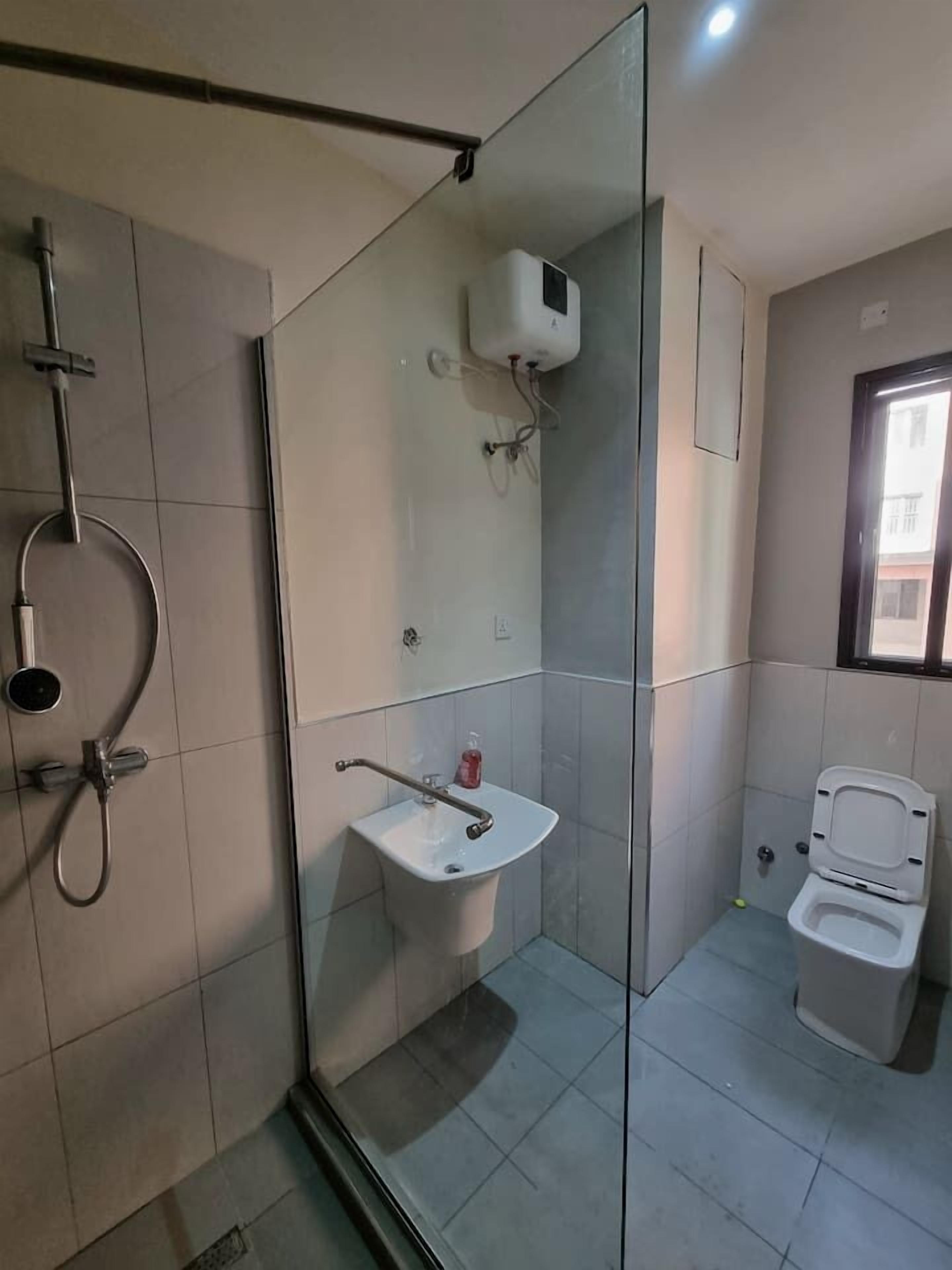 Une salle de bain moderne avec une douche à parois de verre, un lavabo sur colonne et des toilettes.