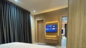 Una habitación de hotel moderna con una cama grande, un televisor de pantalla plana en la pared y un armario de madera.