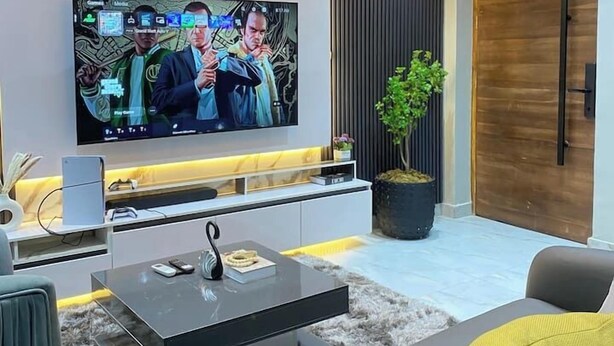 Una sala de estar moderna con un televisor de pantalla plana grande, una mesa de centro y un sofá.
