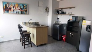 A compact kitchen with a central island, a refrigerator, a microwave, and a coffee maker. - La 70 Laureles Condo cold AC (Medellín)