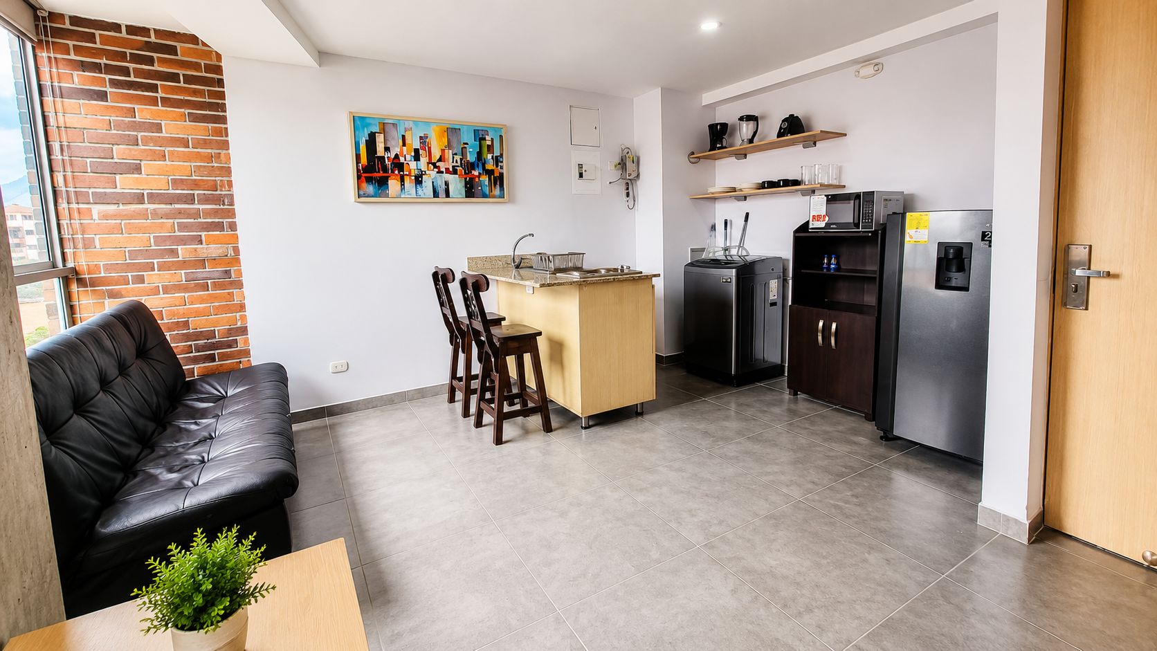 Un espace de vie compact comprenant un coin cuisine, un coin repas et un coin salon.