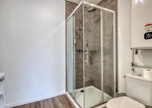 A modern bathroom with a glass-enclosed shower, a toilet, and a sink.