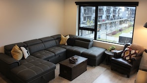 A modern living room with a sectional sofa, a small table, and a chair. - Relax, Explore, Repeat –Your Revelstoke Retreat Awaits, 3 Bedroom, Pet Friendly! (Revelstoke)