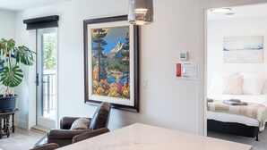 A modern living room with a dining table, a large framed painting, and a potted plant. - Relax, Explore, Repeat –Your Revelstoke Retreat Awaits, 3 Bedroom, Pet Friendly! (Revelstoke)