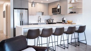 A modern kitchen with a central island, bar stools, and built-in appliances. - Relax, Explore, Repeat –Your Revelstoke Retreat Awaits, 3 Bedroom, Pet Friendly! (Revelstoke)