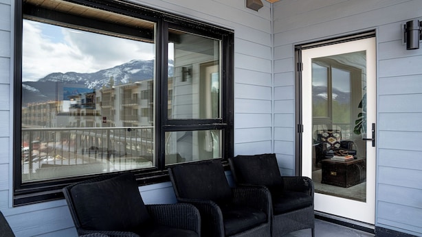 A balcony with wicker chairs, a sliding glass door, and a view of mountains. - Relax, Explore, Repeat –Your Revelstoke Retreat Awaits, 3 Bedroom, Pet Friendly! (Revelstoke)