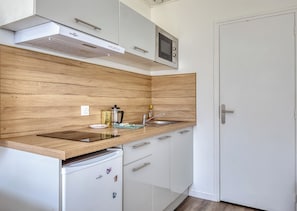 A modern kitchen with a stainless steel microwave, a coffee maker, and a sink.