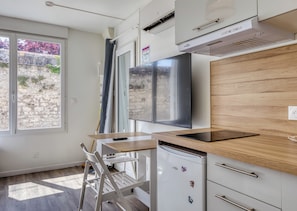 A modern kitchen with a built-in oven, a wooden countertop, a white chair, and a large window.