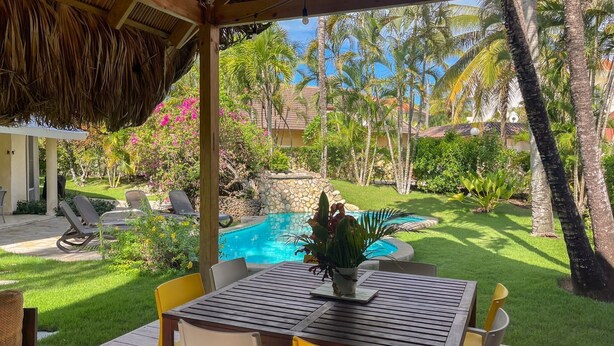 A covered outdoor area with a pool, lounge chairs, and a table with chairs. - Charming oceanfront 3 BR villa in Cabarete Center (Cabarete)