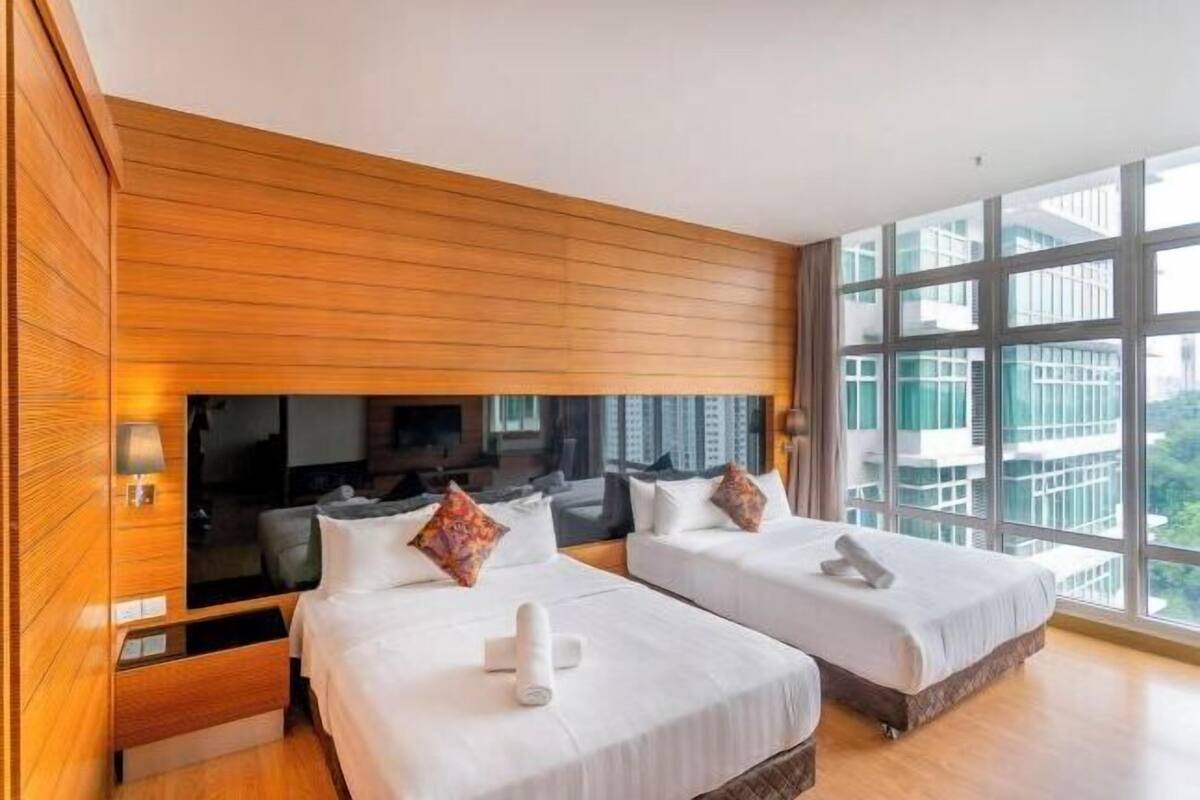 Een hotelkamer met twee bedden, een houten wandpaneel, een groot raam en een flatscreen televisie.