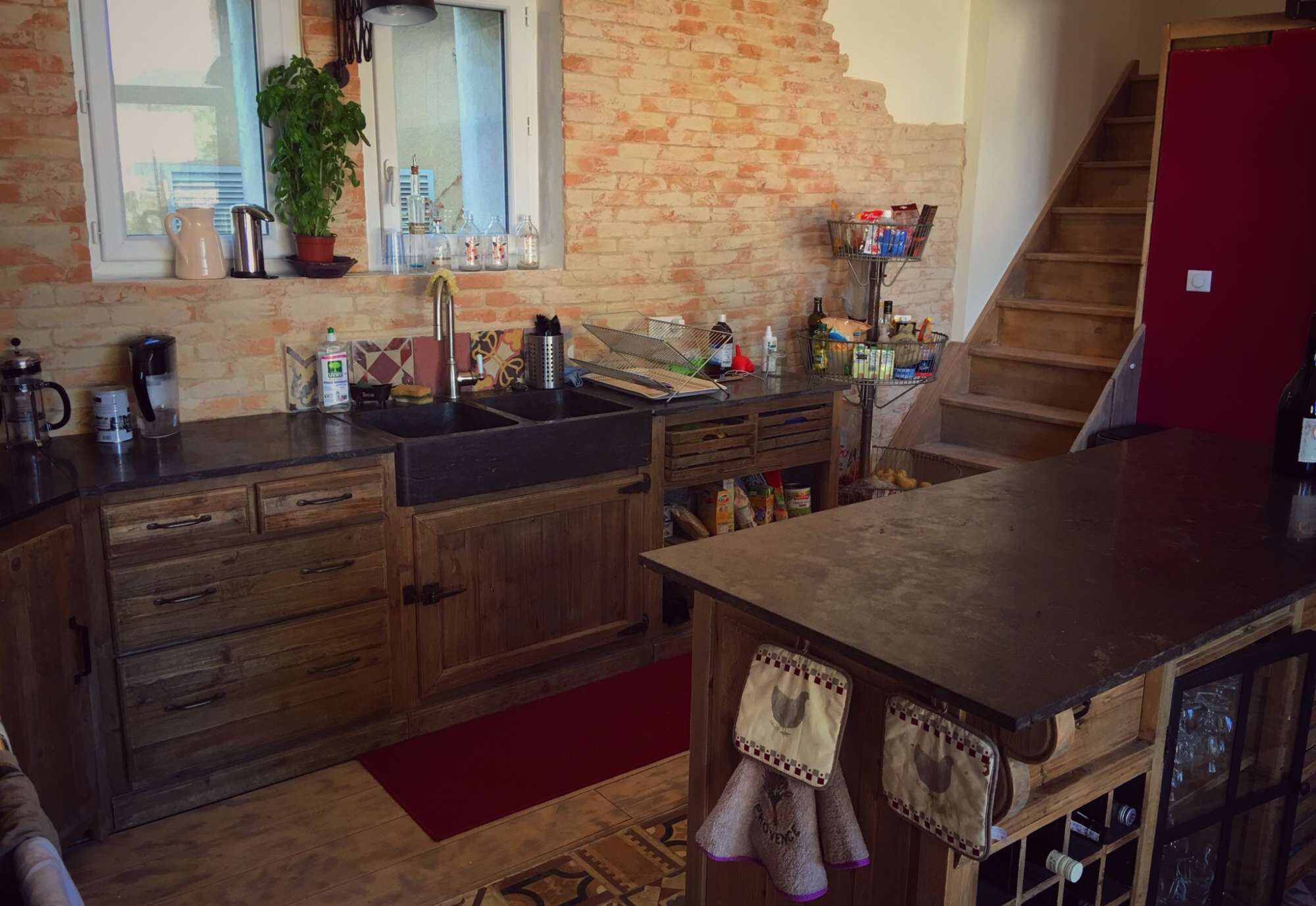 Una cocina con armarios de madera, un lavamanos y una encimera con diversos utensilios.