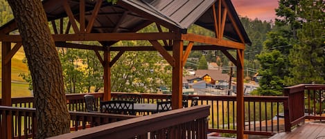 Eine Holzterrasse mit einem Pavillon, Tischen und Stühlen mit Blick auf ein Wohngebiet.