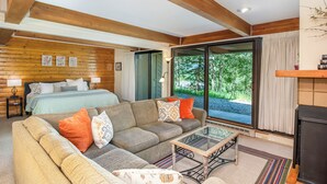 A cozy room with a bed, a sofa, and a glass table. There is a sliding glass door leading to an outdoor area. - Mountain Edge Condo Mt Crested Butte (Crested Butte)