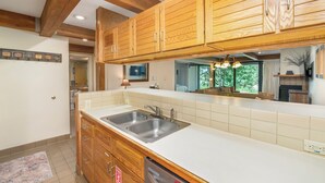 A kitchen with wooden cabinets, a white countertop, and a double sink. - Mountain Edge Condo Mt Crested Butte (Crested Butte)