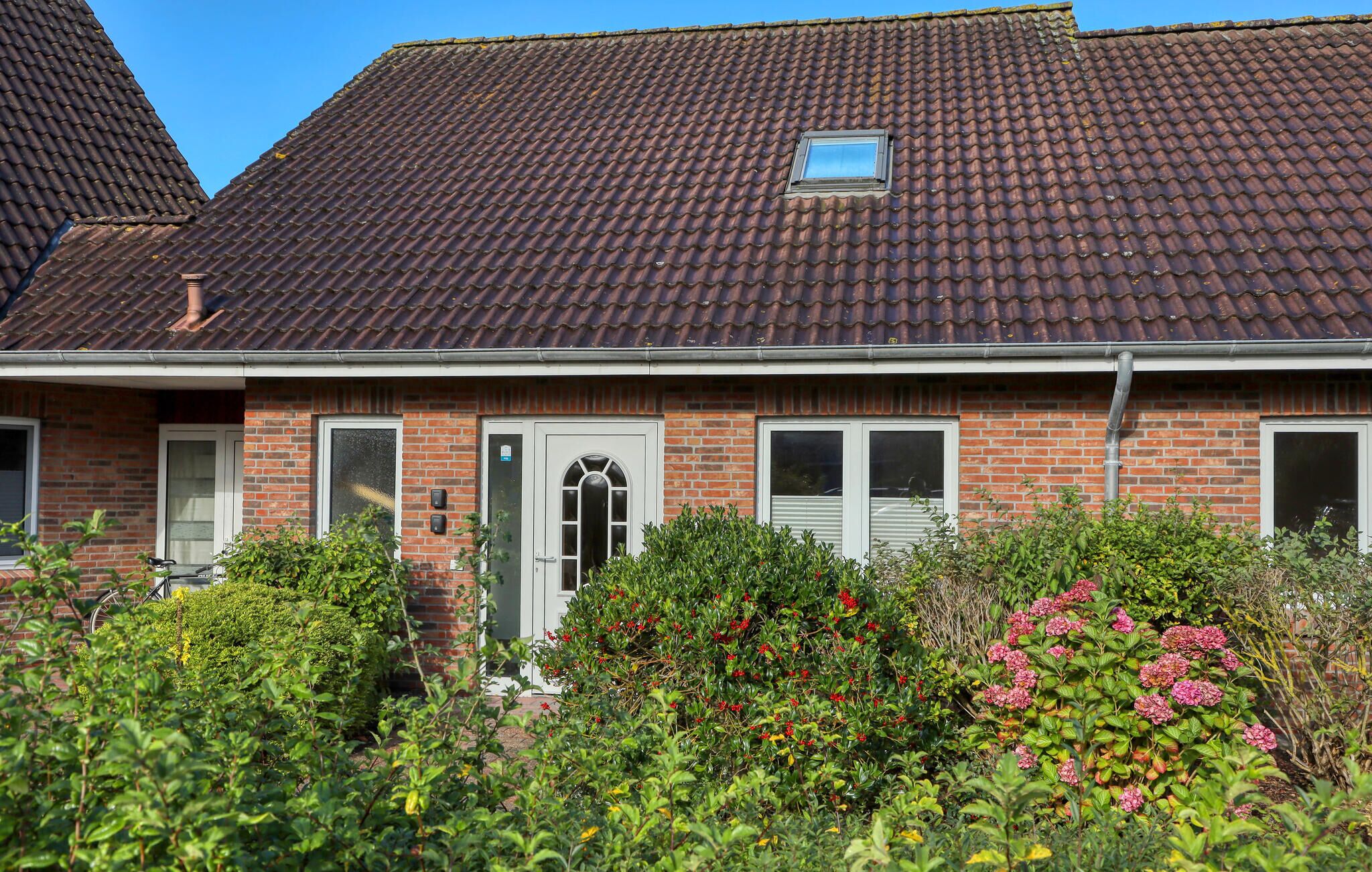 A two-story house with a tiled roof, brick walls, and a front door with a small window above it.