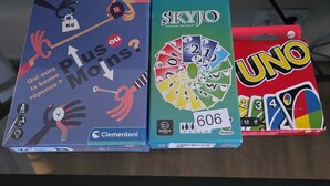 Tres juegos de mesa: 'Plus ou Moins?', 'SKYJO' y 'UNO' sobre una mesa.